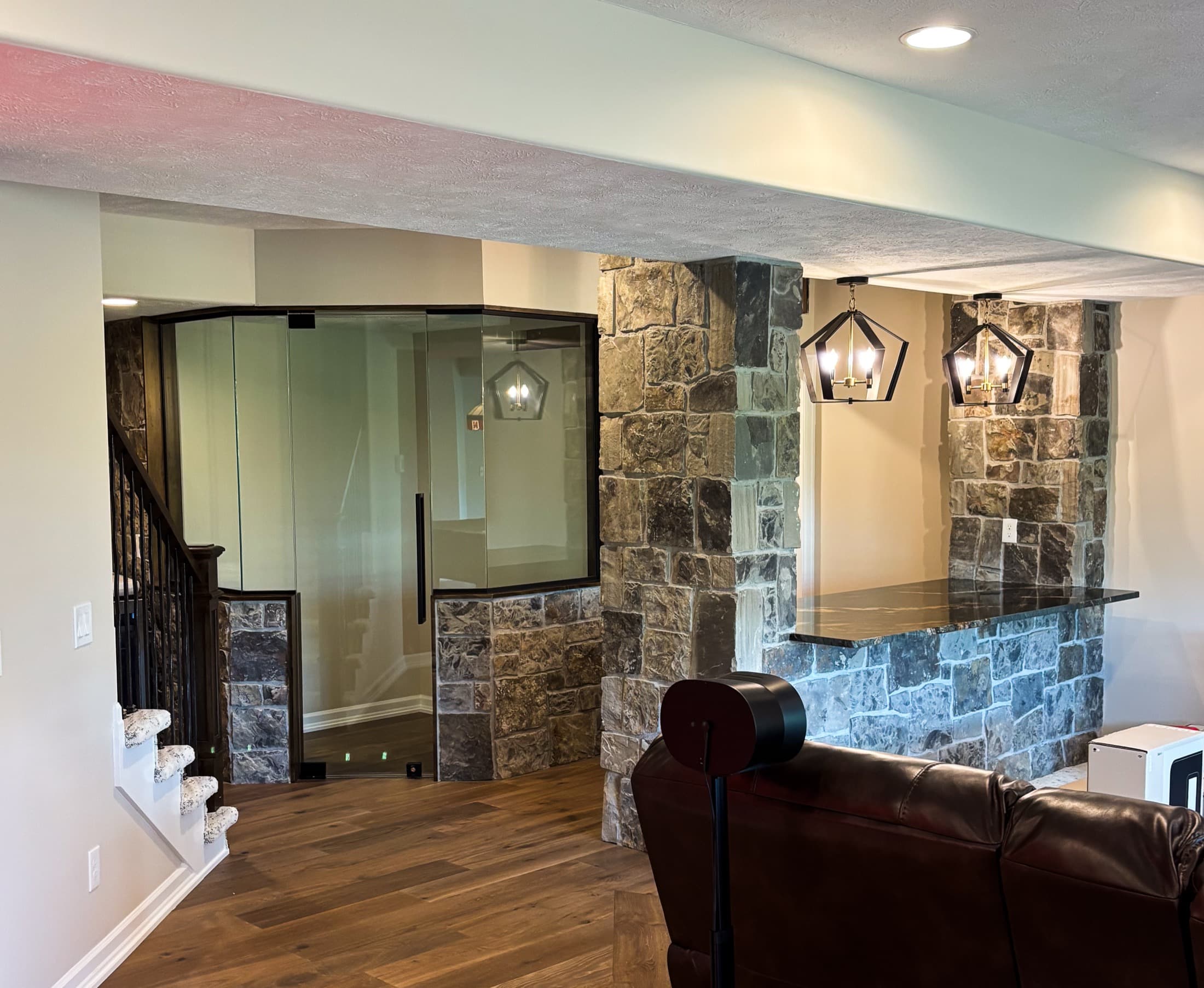 Finished basement with custom stone wet bar and pendant lighting
