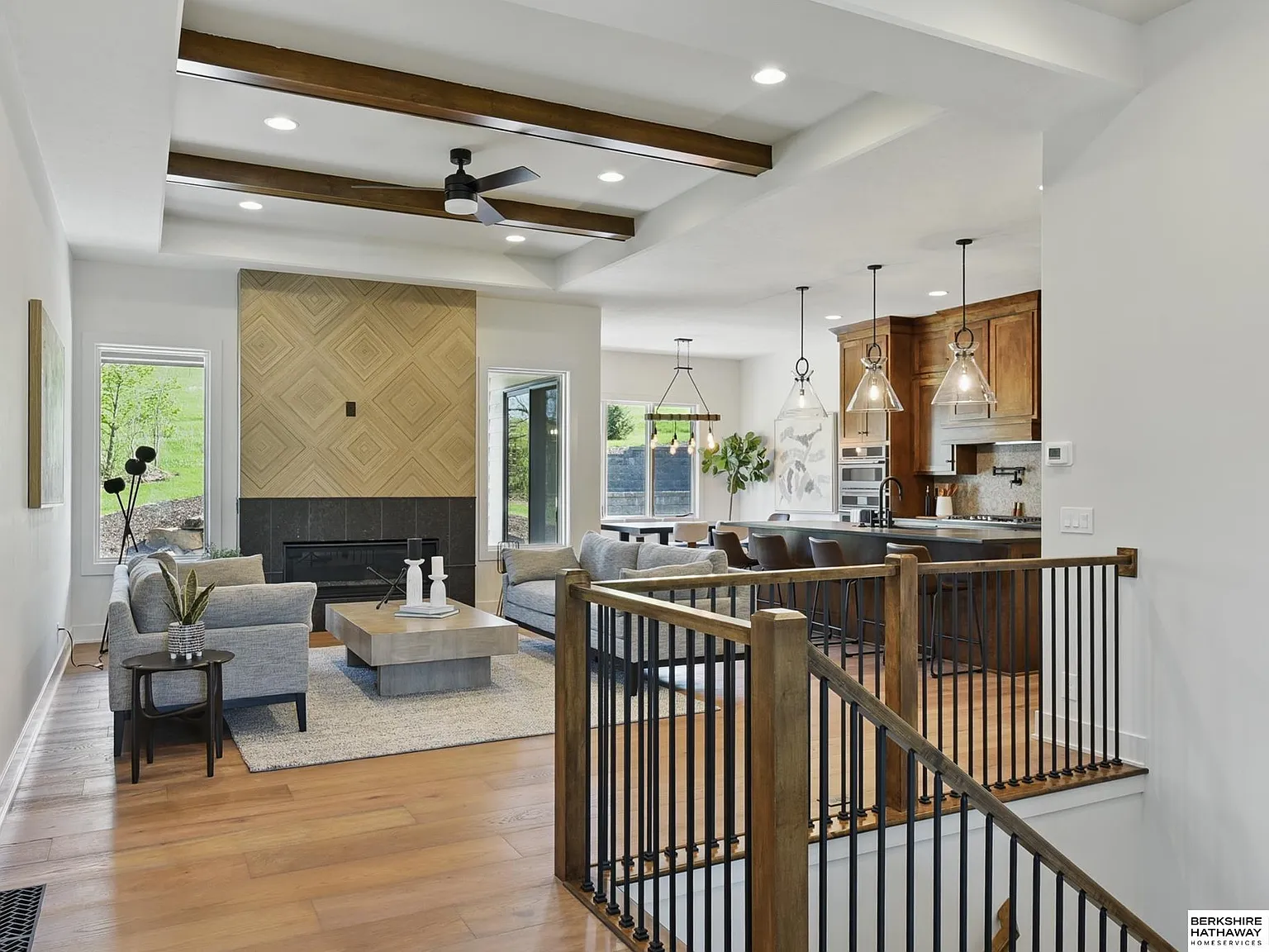 Open-concept living room and kitchen with beamed ceiling and stone fireplace